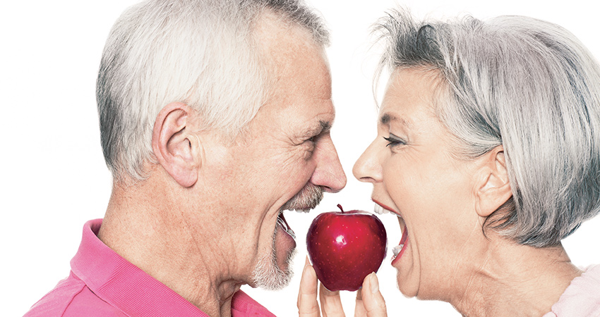 Couple looking at each other and bite same apple
