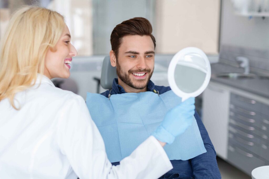 Dentist showing a patient their smile results with a hand mirror.